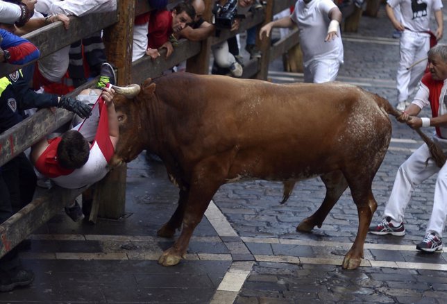 Un toro embiste a un corredor durante el último encierro