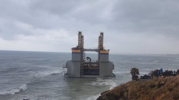 Numerosas personas se acercan a contemplar la estructura marítima varada en una playa de Benalmádena (Málaga)